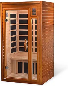 A wooden infrared sauna with a glass door and control panel, featuring interior benches and black heating panels. The sauna exudes a warm, inviting ambiance.