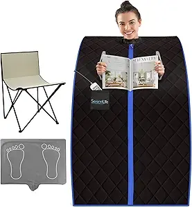 A person in a black sauna suit reading a magazine, accompanied by a folding chair and a foot-shaped mat on a light background.