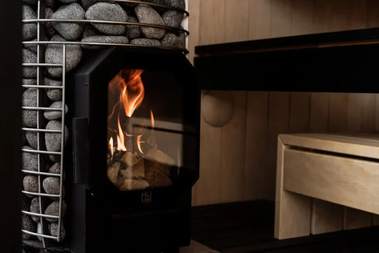 How hot should authentic saunas be? This glowing wood stove demonstrates the heat source that maintains proper sauna temperatures against aromatic wooden walls.