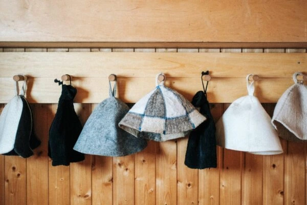 Exploring what is a sauna hat – a wooden wall showcases wool caps and wide-brimmed styles for optimal sauna comfort