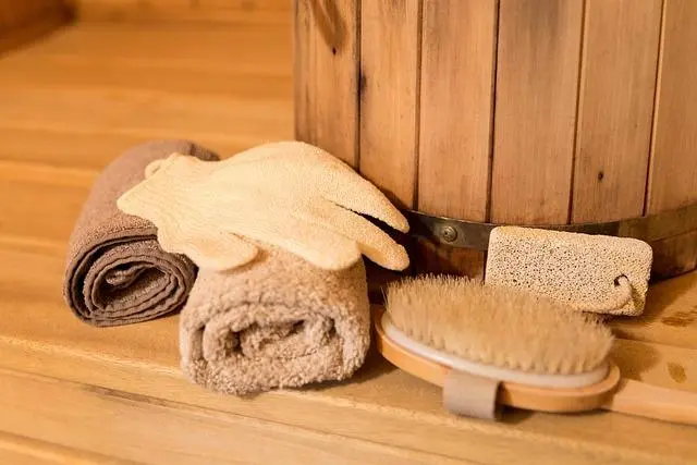 How do you clean a sauna? A wooden sauna bench with towels and a cleaning brush, ready for maintenance and relaxation.