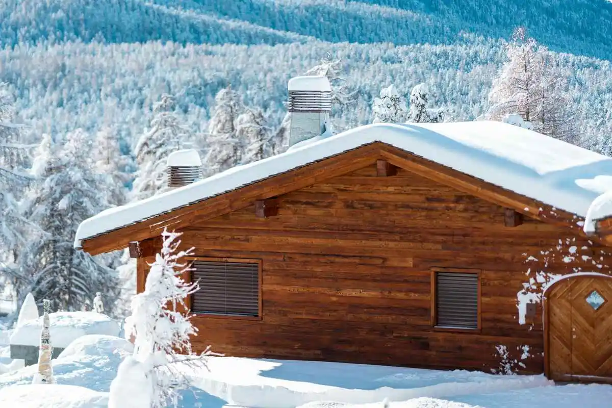 A snow-covered wooden cabin with a sauna, illustrating the question: Is sauna good for a cold?