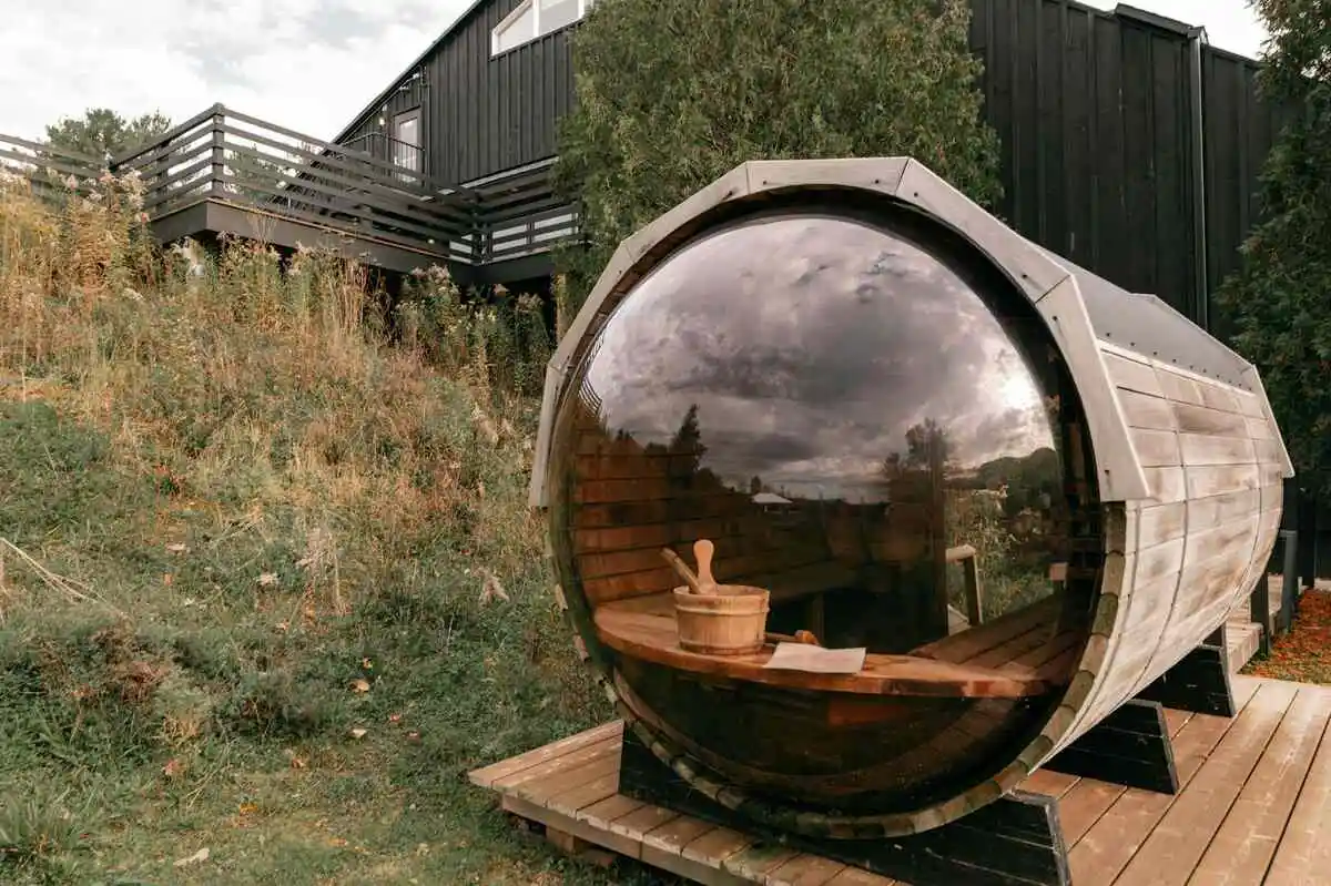 A modern glass bubble sauna on a wooden deck, illustrating an outdoor relaxation space. Perfect for those wondering how long should you sit in a sauna—typically 15-20 minutes for optimal benefits.