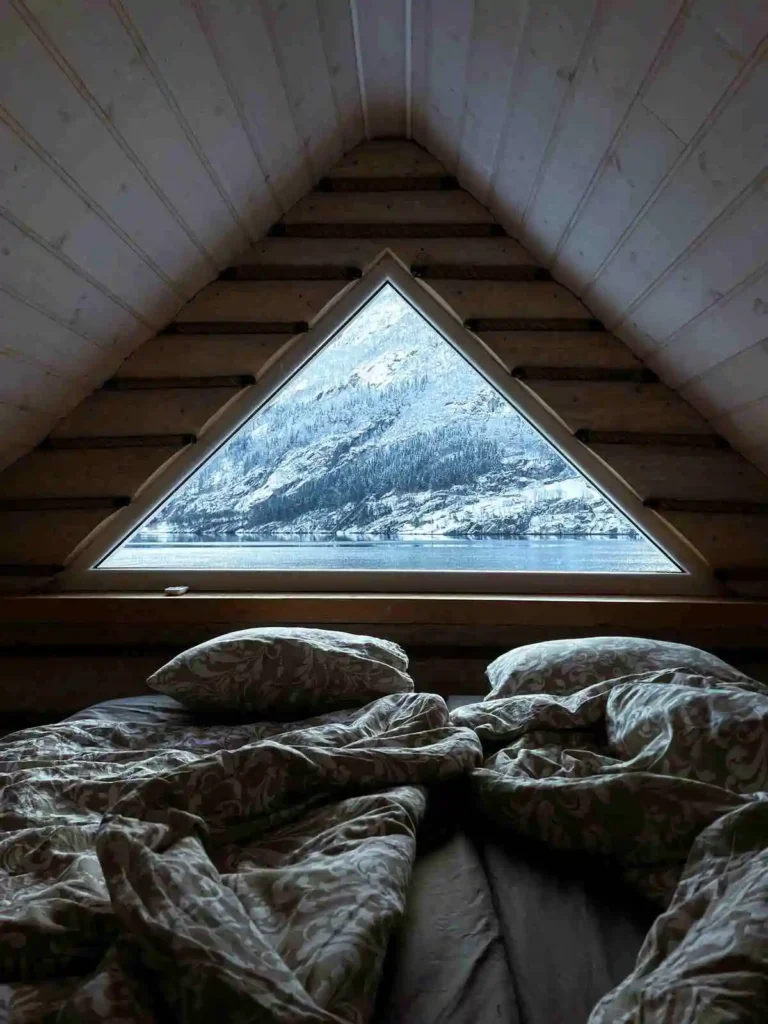 Rustic cabin bedroom with bed near window, showcasing natural lighting - perfect relaxation space after considering how long to wait to shower after infrared sauna.