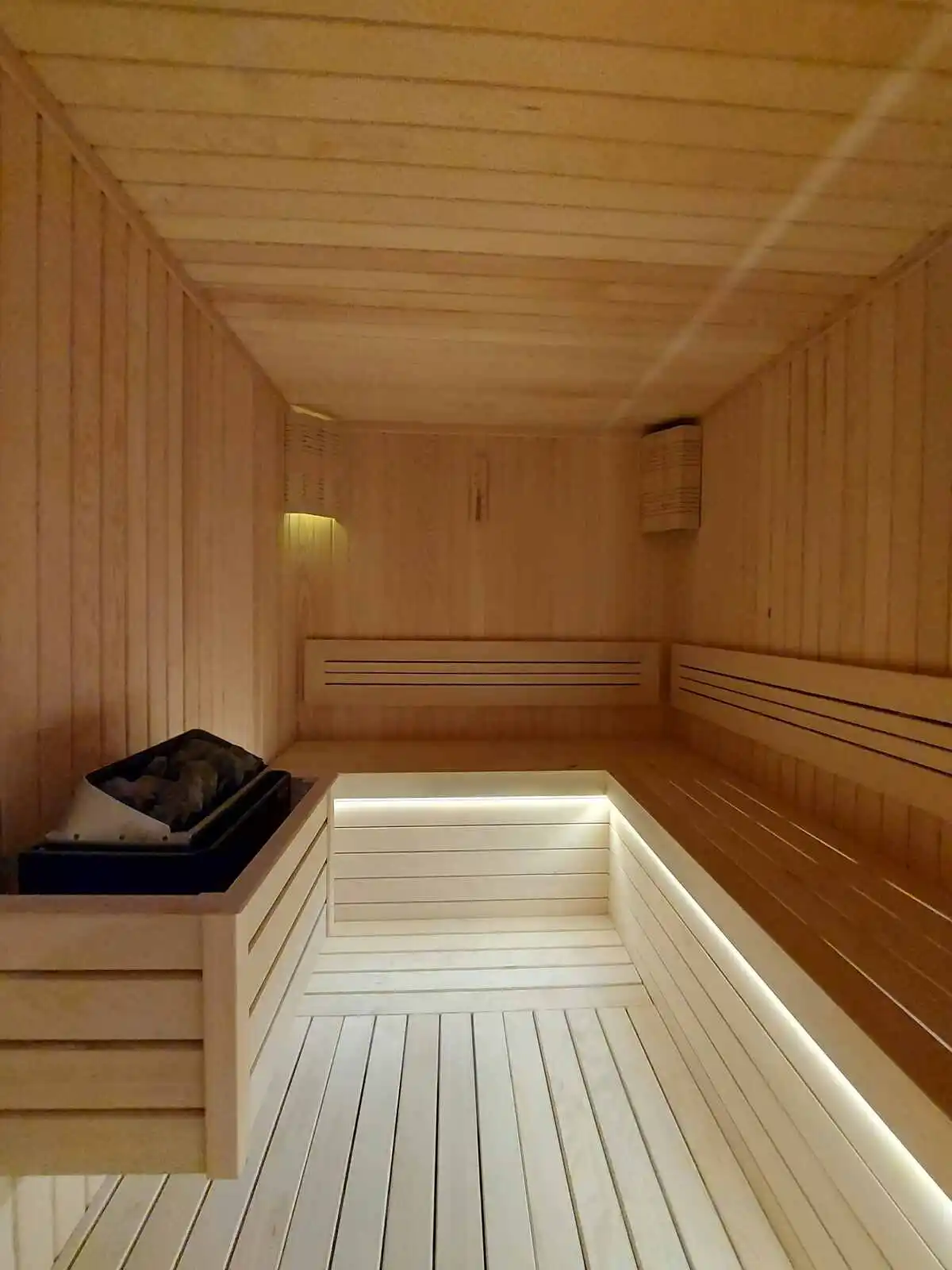how much water weight can you lose in a sauna, A sauna room featuring a wooden bench and a small sink against the wall.