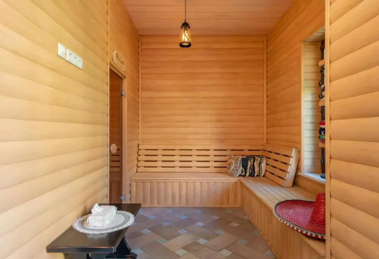 Wooden infrared sauna interior with bench and table—explore whether an infrared sauna is better than a regular sauna for relaxation.