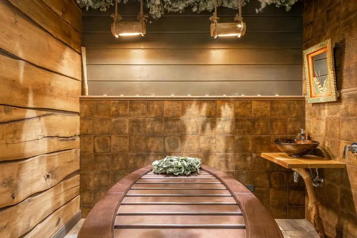 A cozy bathroom with a wooden floor and bench, perfect for a daily sauna routine. Is it good to sauna every day? Discover the benefits of this warm, natural retreat.