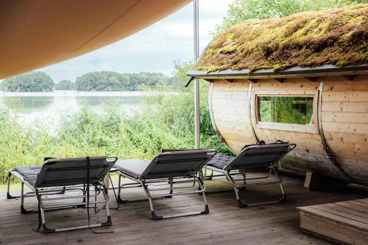 A wooden house with a grass-covered roof, blending into nature. Nearby, a sauna poses the question: is the sauna good for high blood pressure?